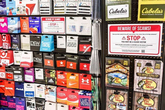 A gift card stand displays scam warning.